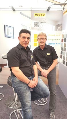 Zwei Mitarbeiter von Weru präsentieren energieeffiziente Fensterlösungen am Messestand.